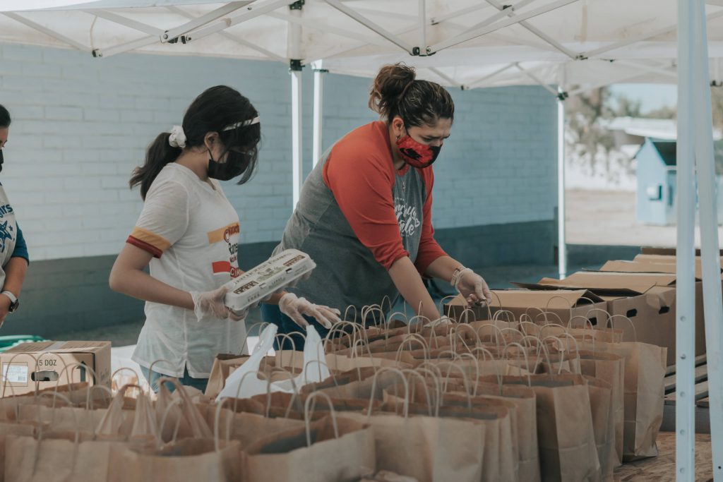 Volunteers packing food parcels. Both are wearing face masks.